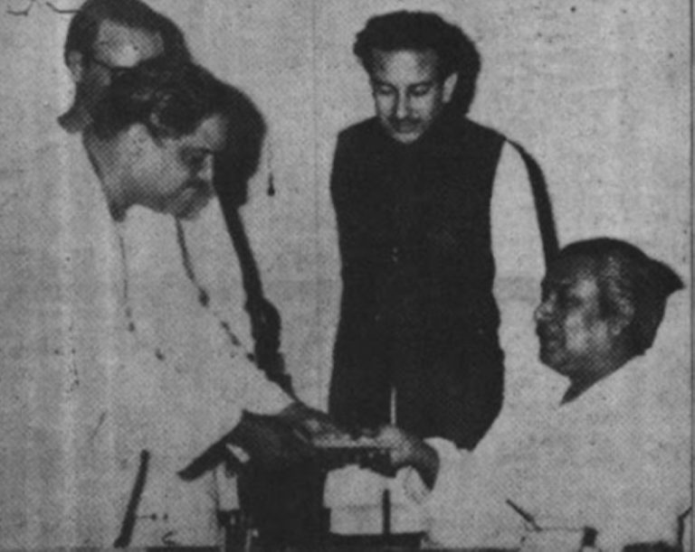 বঙ্গবন্ধুর হাতে চেক তুলে দিচ্ছেন তথ্য ও বেতার মন্ত্রী এম কোরবান আলী, পাশে মুজিব কোট পরিহিত তাহের উদ্দিন ঠাকুর